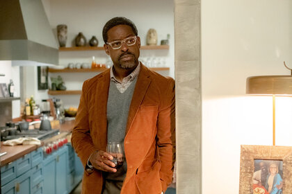 Randall leaning against a doorway with a cup in his hand