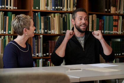 Zachary Levi sitting next to a woman at a table, smiling