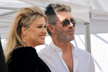 Kelly Clarkson posed and smiling with Simon Cowell