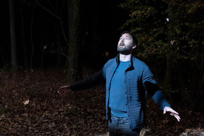 Max in the woods looking up at a bright light off camera