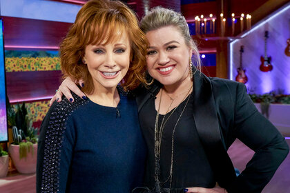 Kelly Clarkson and Reba hugging and smiling at the camera