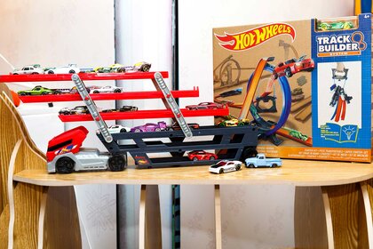 Hot Wheels toys next to a Hot Wheels box on a table.