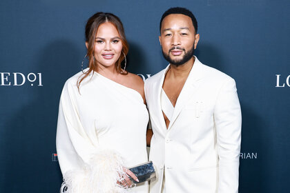 John Legend and Chrissy Teigen pose on a red carpet