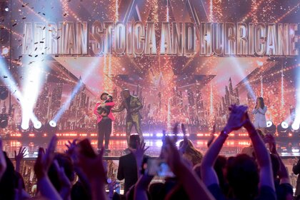 Audience members celebrating as Adrian Stoica and Hurricane celebrate with Terry Crews on stage.