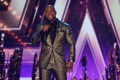 Terry Crews talking into a mic on stage during America's Got Talent.