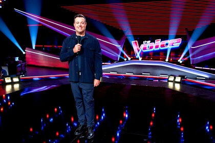 Carson Daly stands on The Voice stage during the premiere episode