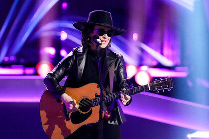 Jordan Rainer performs on The Voice Stage while wearing dark black sunglasses and playing guitar