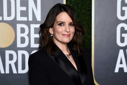 Tina Fey posing on the Golden Globes red carpet wearing an all black blazer.