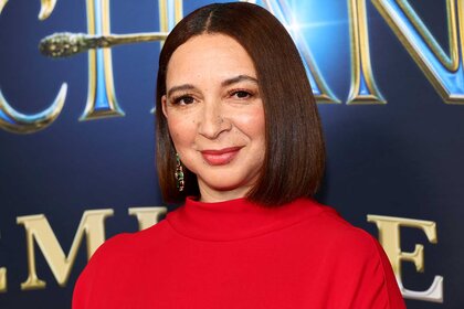 Maya Rudolph, wearing a red top and smiling at the camera, attends the Disenchanted movie premiere.