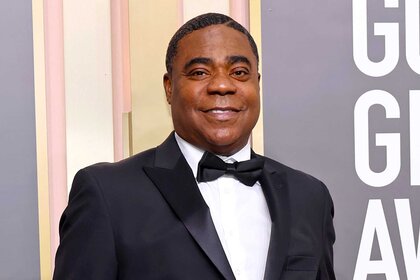 Tracy Morgan, wearing a black suit with a bowtie, smiles at the camera at the 80th Annual Golden Globe Awards.