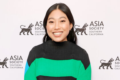 Awkwafina smiles on a red carpet at an event