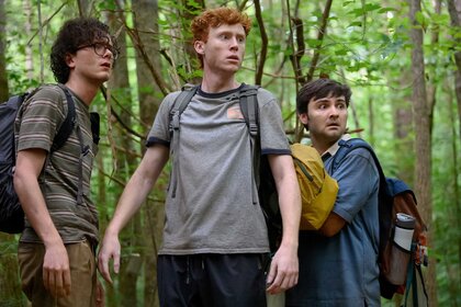 Martin, Ben, and John huddling together in the forest and looking frightened.