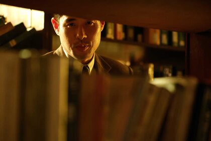 A close-up of Dr. Ben Song looking through a row of books.