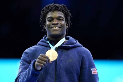 Frederick Richard sniles holding his Bronze Medal.