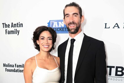 Michael and his wife Nicole Phelps wears a white dress and smiles together