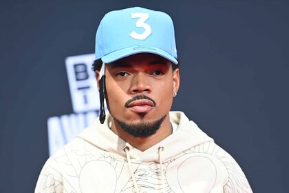 Chance the Rapper poses in a hoodie and his signature "3" hat.