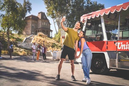 People take a selfie next to Universal Studios backlot tram.