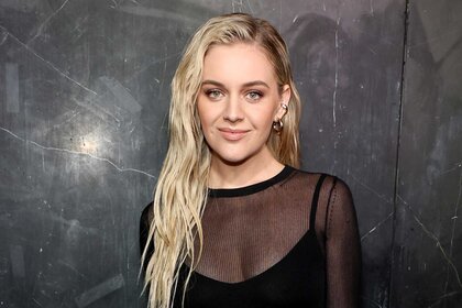 Kelsea Ballerini smiles in a black sheer top at a fashion show