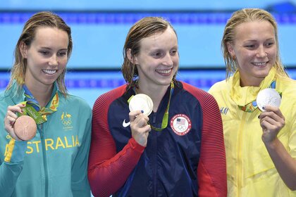 Katie Ledecky, Sarah Sjostrom, and Emma McKeon hold up their medals.