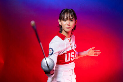 Lee Kiefer holding a foil and standing in front of a colorful backdrop.