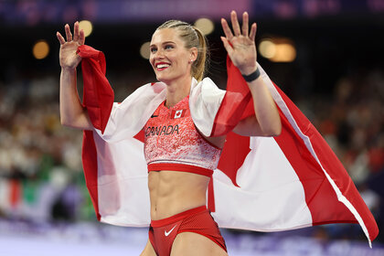 Alysha Newman running and waving with the Canadian flag at the Paris 2024 Olympics.