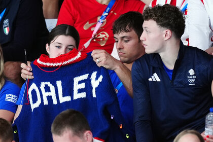 Tom Daley shows off his sweater he was knitting in the stands