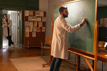 Dr Oliver Wolf writes on a chalk board on Brilliant Minds Episode 101