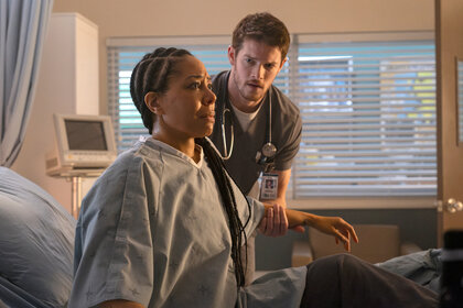 Jessie Williams sits in a hospital bed with Dr Van Markus helping on Brilliant Minds Season 1 Episode 2.