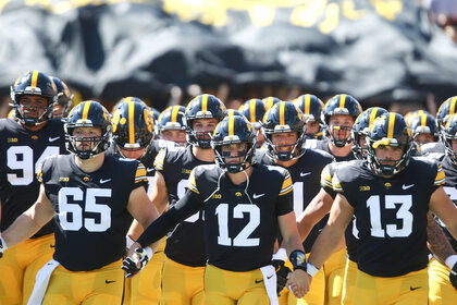 Quarterback Cade McNamara of the Iowa Hawkeyes leads the team onto the field before the first half against the Utah State Aggies