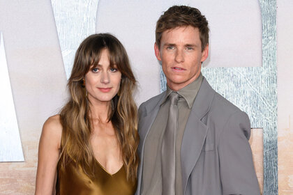 Hannah Bagshawe wears a brown silk dress next to Eddie Redmayne