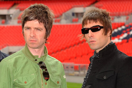 Oasis' Noel Gallagher and Liam Gallagher pose together in a stadium.