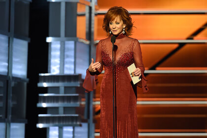 Reba McEntire onstage in a red dress as she hosts the 53rd Academy of Country Music Awards