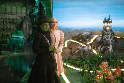 Elphaba and Glinda hold hands and look out to oz in Wicked