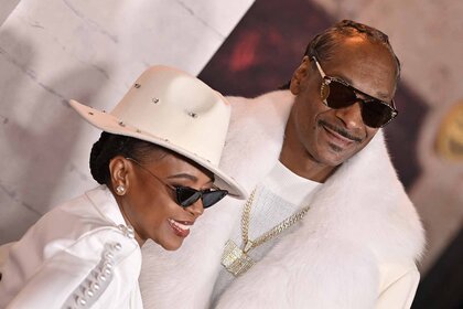 Shante Broadus and Snoop Dogg smile together in matching all-white outfits.