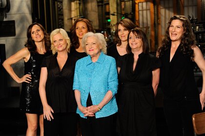 Betty White wears a blue shirt amongst the women of the cast who are wearing black on Saturday Night Live Episde 1575.