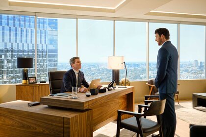 Ted Black sitting at a desk while speaking to Rick Dodsen on Suits L.A. Season 1, Episode 1.