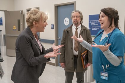 Notery (Steve Little) watches as Joyce (Wendi Mclendon Covey) and Alex (Allison Tolman) chat in a hallway.