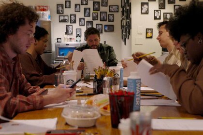 Writers work together at a cluttered table on SNL50: Beyond Saturday Night Episode 102.