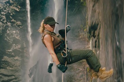 Zora Bennett (Scarlett Johansson) rappels down a cliff next to a waterfall in Jurassic World Rebirth (2025).