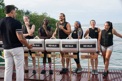 The cast stands on a deck with their briefcases on Deal or No Deal Island Season 2 Episode 6.