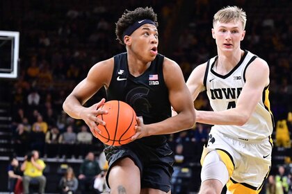 Jeremy Fears Jr. of the Michigan State Spartans leaping to take a shot as Josh Dix of the Iowa Hawkeyes defends in during a Big Ten Conference basketball game.