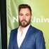 Patrick John Flueger poses in a blue-grey suit.