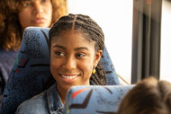 Deja on This Is Us sitting in a coach bus seat, smiling