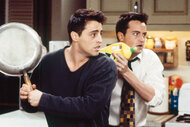 Joey and Chandler holding a pan and a bottle of soap on Friends