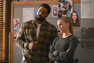 Kevin Atwater and Hailey Upton stand in front of a bulletin board in the squad room on Chicago PD 1104