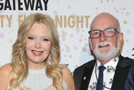 Melissa Peterman and John Brady smiling together in front of a step and repeat.