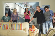 The cast of modern family are all in the dunphy living room where Jay is holding Phil