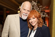 Rex Linn embraces Reba McEntire at a reception event for happy's place