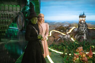 Elphaba and Glinda hold hands and look out to oz in Wicked