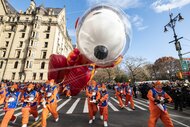 Balloon handlers guide the Peanuts Astronaut Snoopy balloon to fly safely.